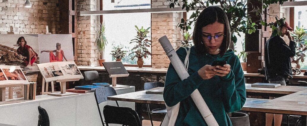 Image shows a young woman on her phone in an office space [Gen Z]