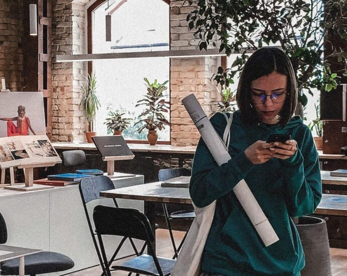 Image shows a young woman on her phone in an office space [Gen Z]