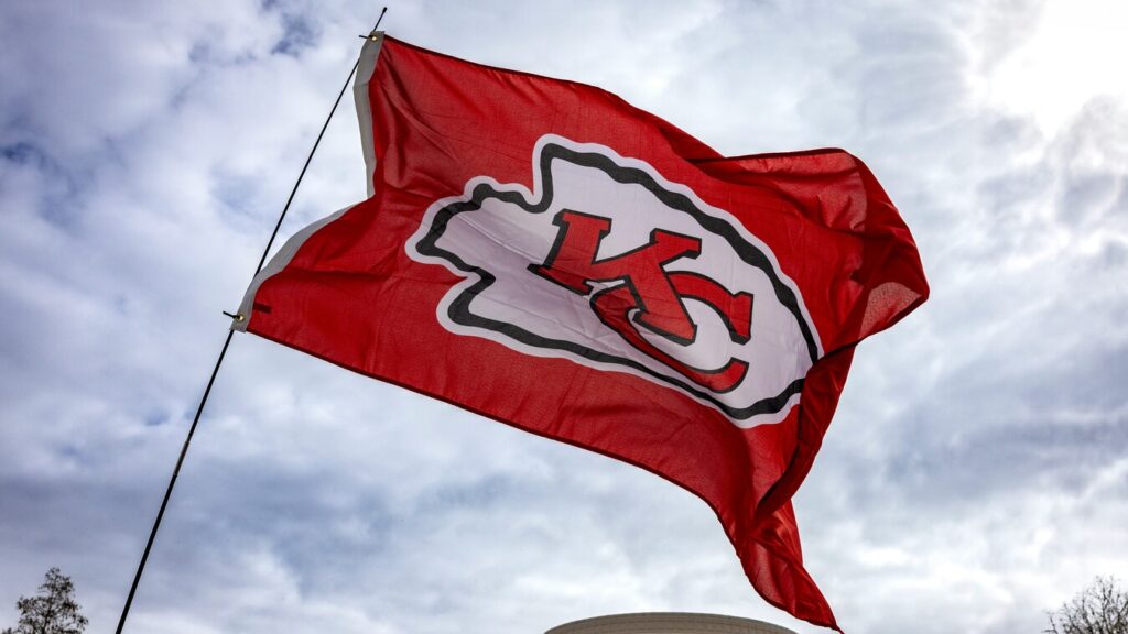 Kansas City Chiefs flag flying in front of building and cloudy sky