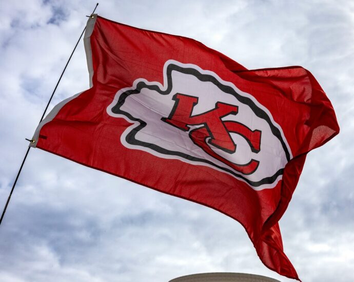Kansas City Chiefs flag flying in front of building and cloudy sky