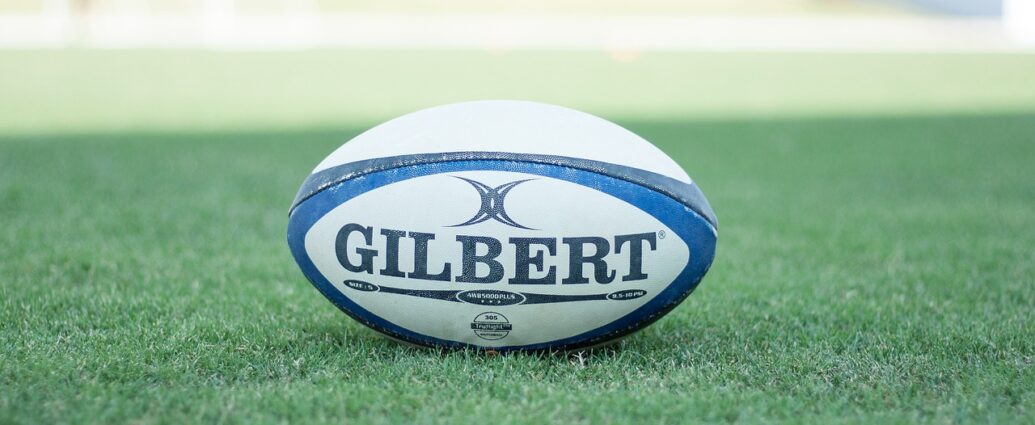 Blue and white rugby ball placed on green grass at Six Nations rugby pitch