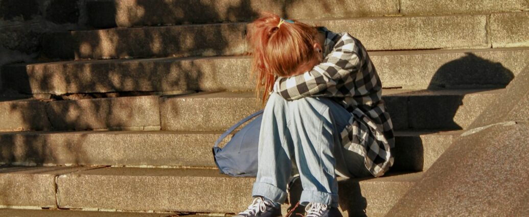 Image shows a young girl crying into her knees [children's mental health crisis]