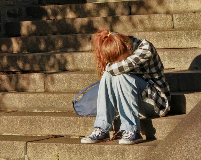 Image shows a young girl crying into her knees [children's mental health crisis]
