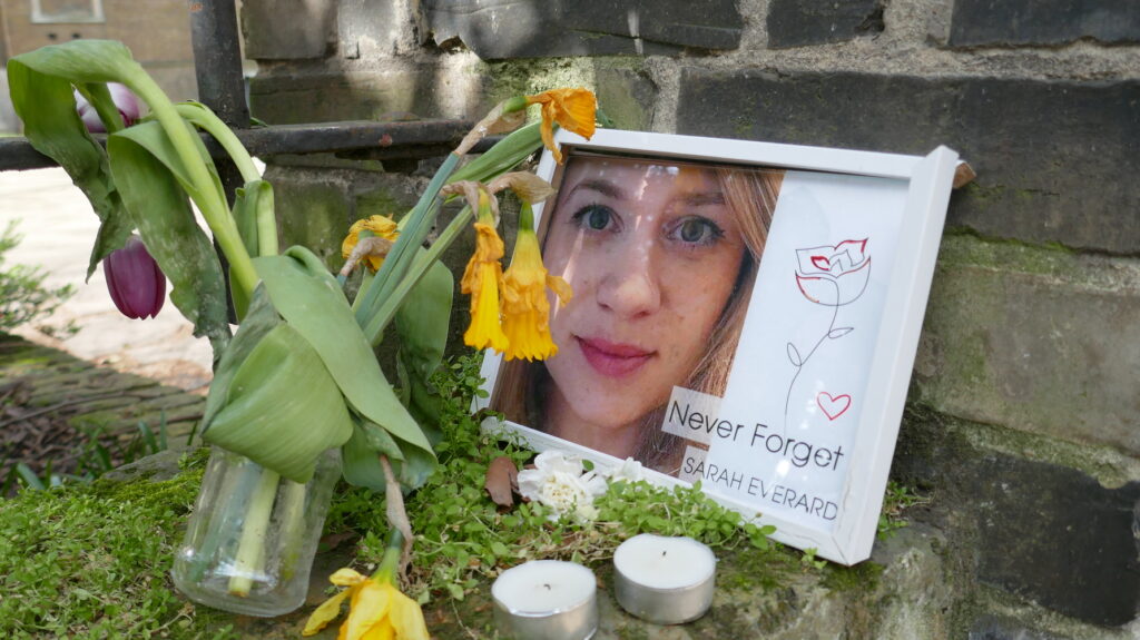 A memorial for Sarah Everard, surrounded by flowers and candles, with an image reading "Never Forget Sarah Everard". [Labour Proposes Mandatory Sexual Violence Training For Police]