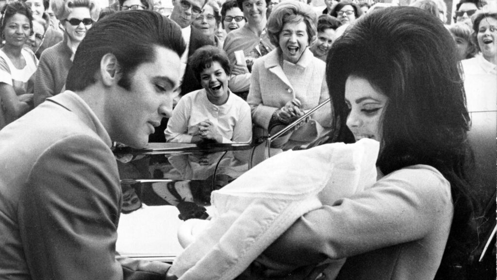 Black and white image of Elvis Presley and Priscilla with Lisa Marie, February 1968