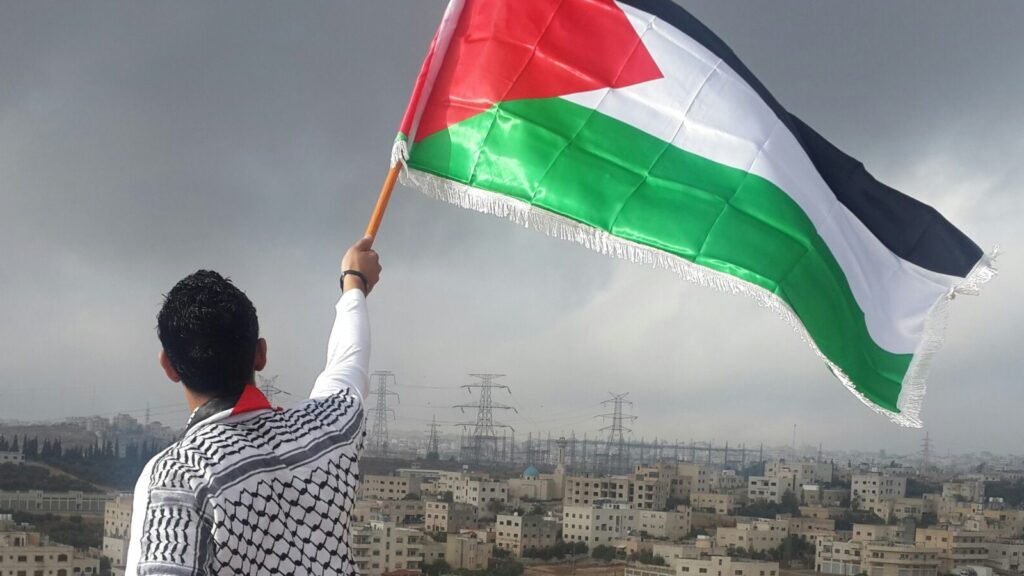 Image of man holding Palestinian flag.