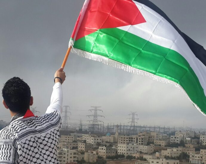 Image of man holding Palestinian flag.