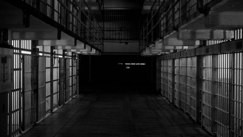 Black and white image shows two rows of prison cells.