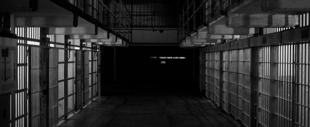 Black and white image shows two rows of prison cells.