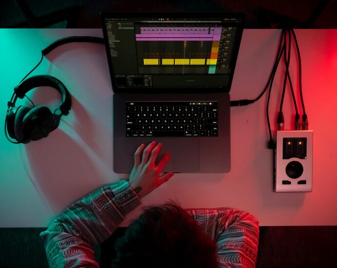 A person sitting in front of a desk with a laptop and headphones working on media leaks