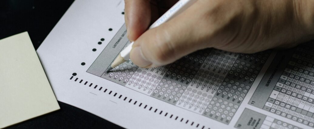 Image shows a hand filling in a multiple choice exam paper [English test scandal].