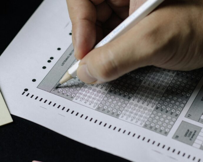 Image shows a hand filling in a multiple choice exam paper [English test scandal].