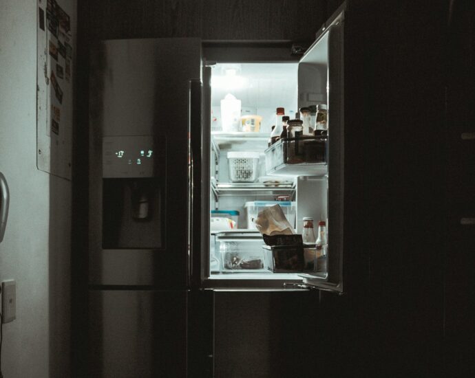 An open fridge shining light in a dark room.