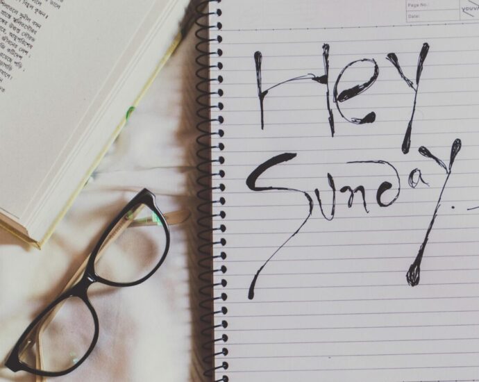 A notepad with writing saying 'Happy Sunday' next to a pair of glasses. Sunday Reset