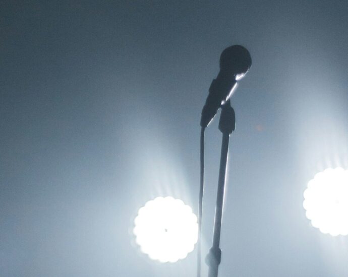 Image shows a microphone under stage lights [Touring]