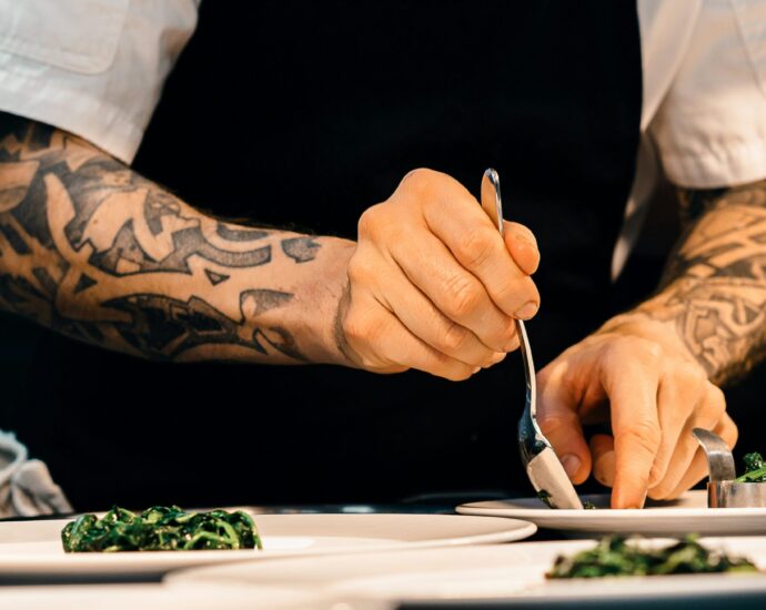 tattooed chef's arms plating up dish