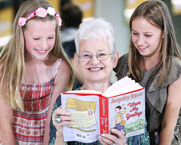 Jacqueline Wilson holding a book smiling
