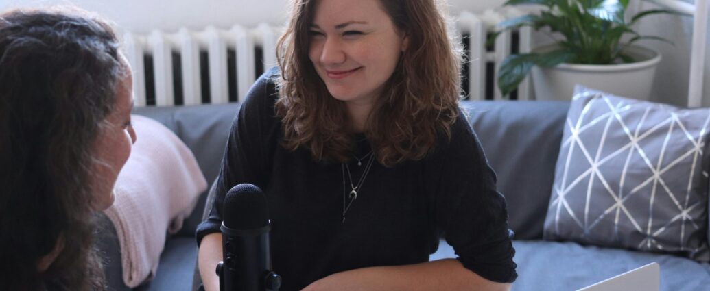 Journalist with a microphone smiles to an interviewee.
