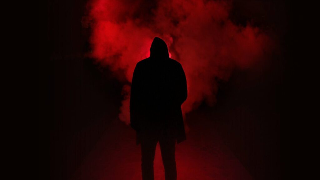 A shadowy figure stands in front of a red fog. Why are some of the "red-pilled" commentators of the "manosphere" women?