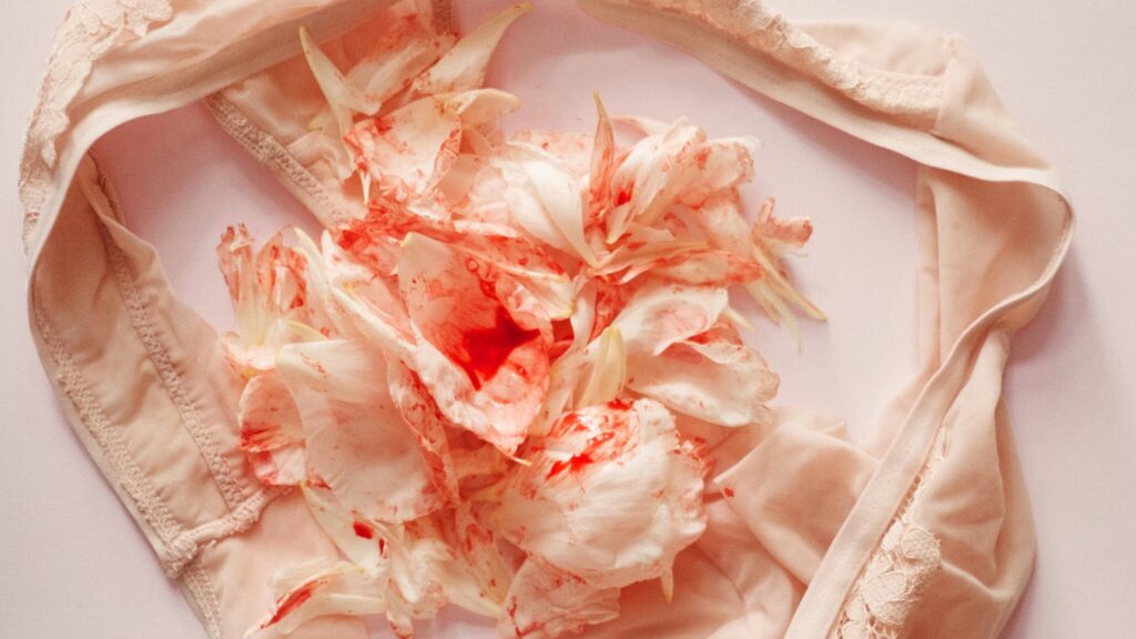 A pair of underwear with mottled red flowers in the middle that gives the illusion of menstrual bleeding.