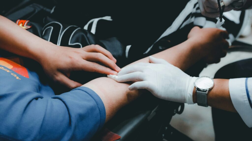 A doctor's hand applying pressure to the vein in someone's arm where their blood has been taken