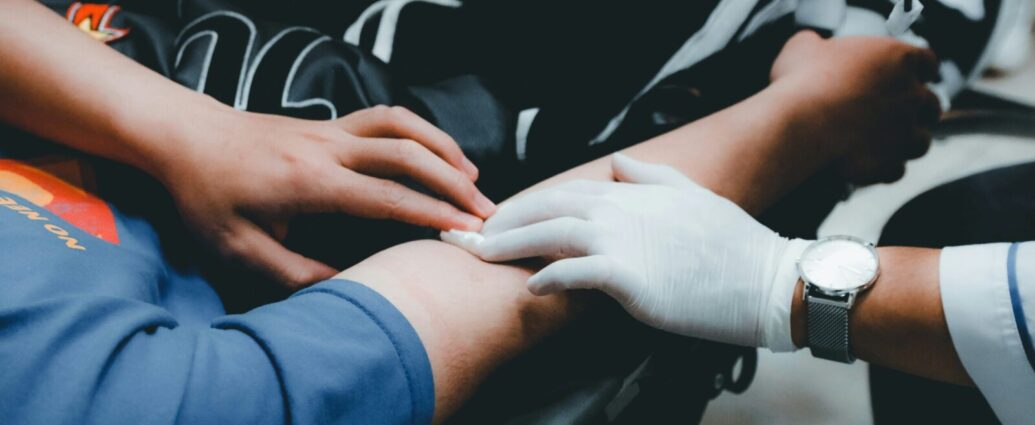 A doctor's hand applying pressure to the vein in someone's arm where their blood has been taken