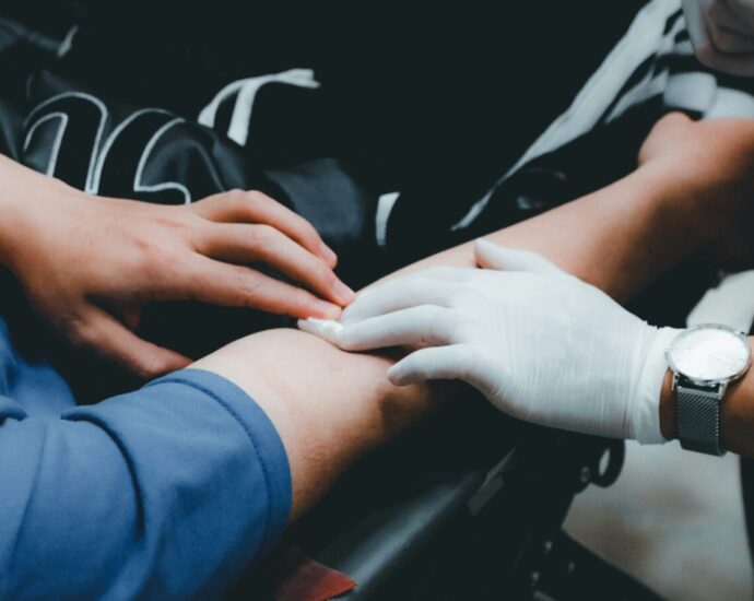 A doctor's hand applying pressure to the vein in someone's arm where their blood has been taken