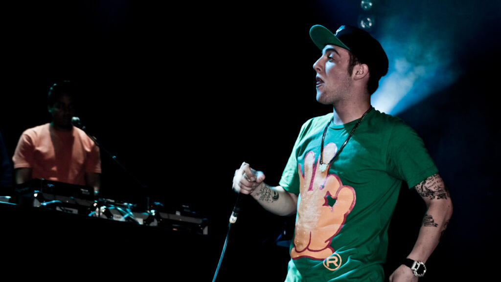 Artist and rapper Mac Miller performing at a concert on stage in green t-shirt. Promoting Balloonerism album