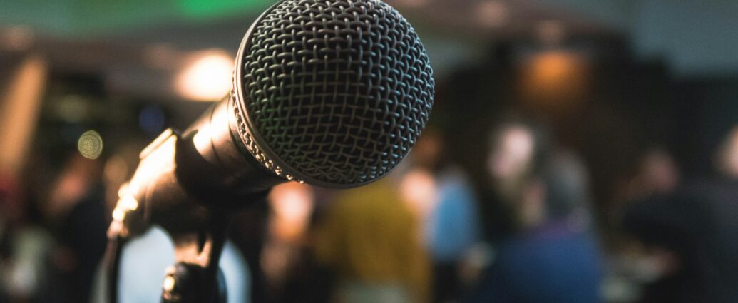 Microphone on stage with people blurred in the background.