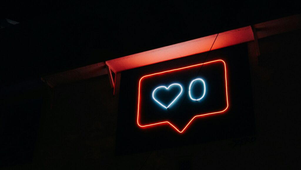 Neon sign depicting an outline of an Instagram 'like' social media symbol