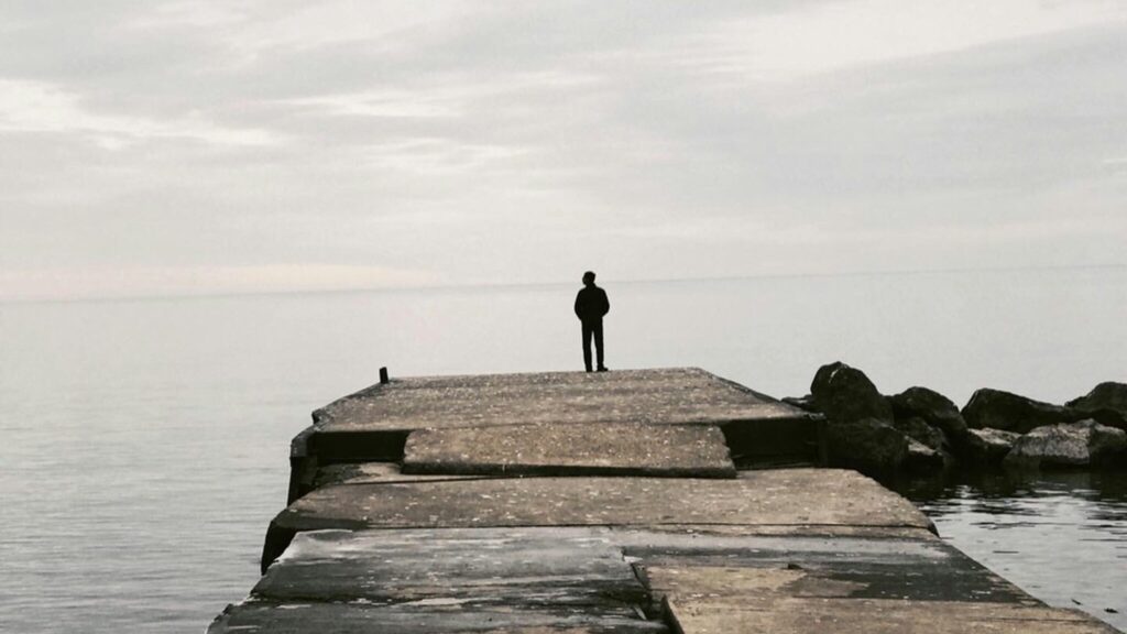 Silhouette of a man standing at a water's edge alone - can we combat extreme misogyny