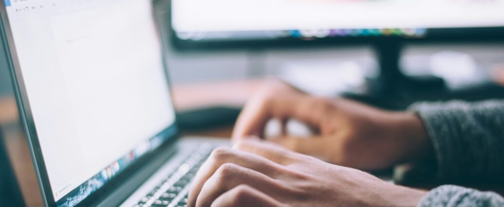 A person typing and doing research on a laptop.