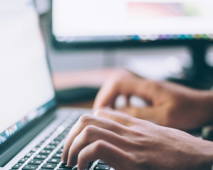 A person typing and doing research on a laptop.