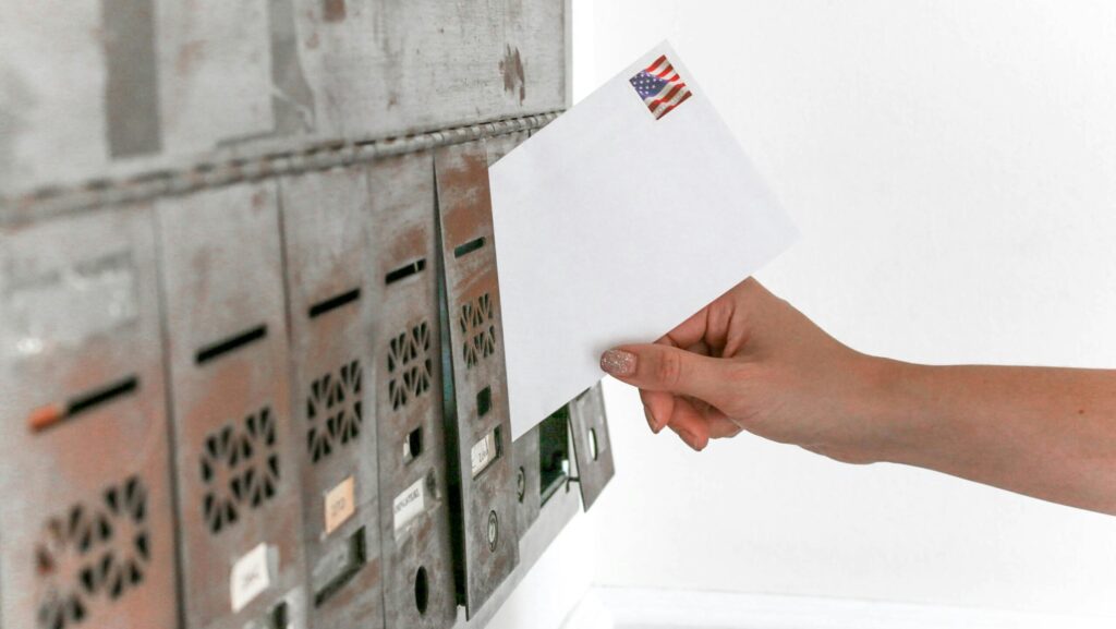 Person posting white envelope