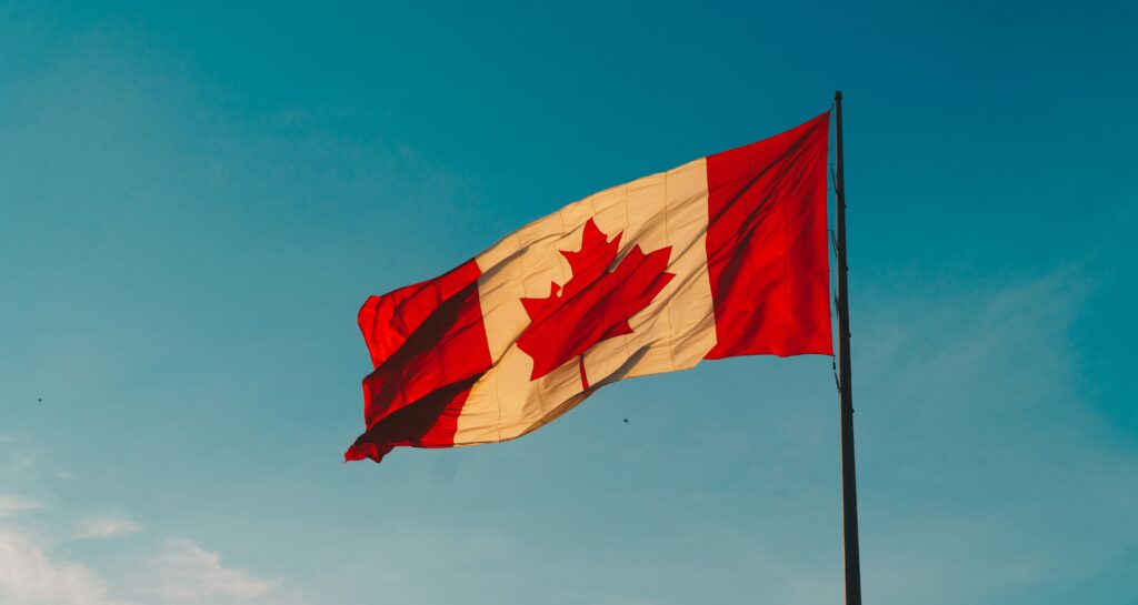 A Canadian flag flies against a blue sky. The image is used in this artilce to symbolise Canadian citizenship and Elon Musk.