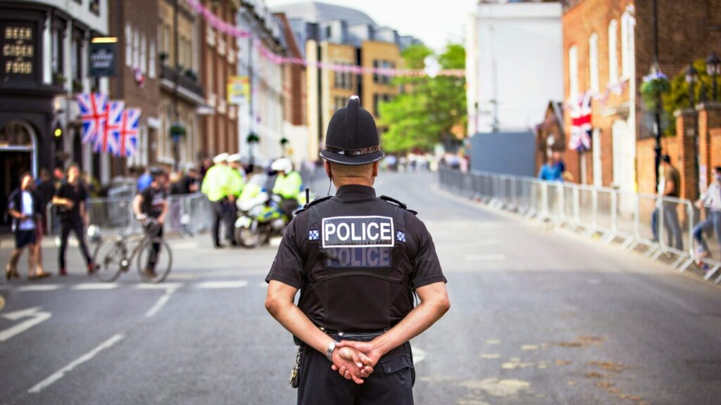 Police officer standing in a community with his arms behind his back.