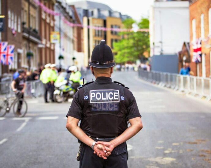 Police officer standing in a community with his arms behind his back.