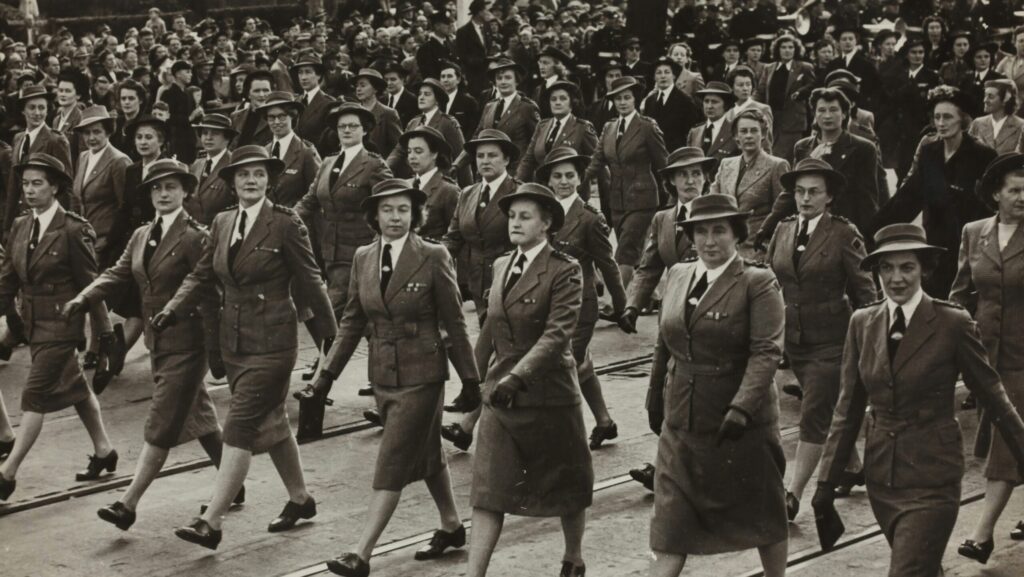 Vintage picture of women in military-like uniforms marching in a row.