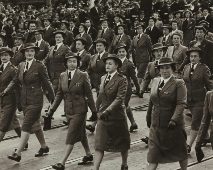 Vintage picture of women in military-like uniforms marching in a row.