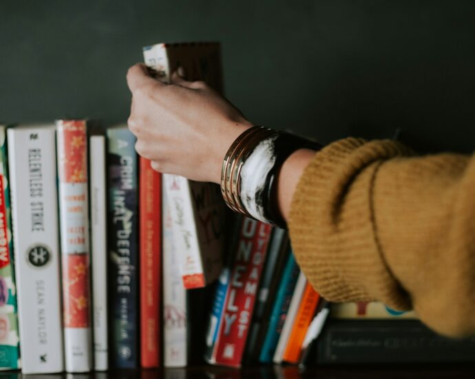 Person picking books from bookshelf