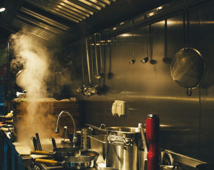 An industrial kitchen with large pots cooking on the stove.